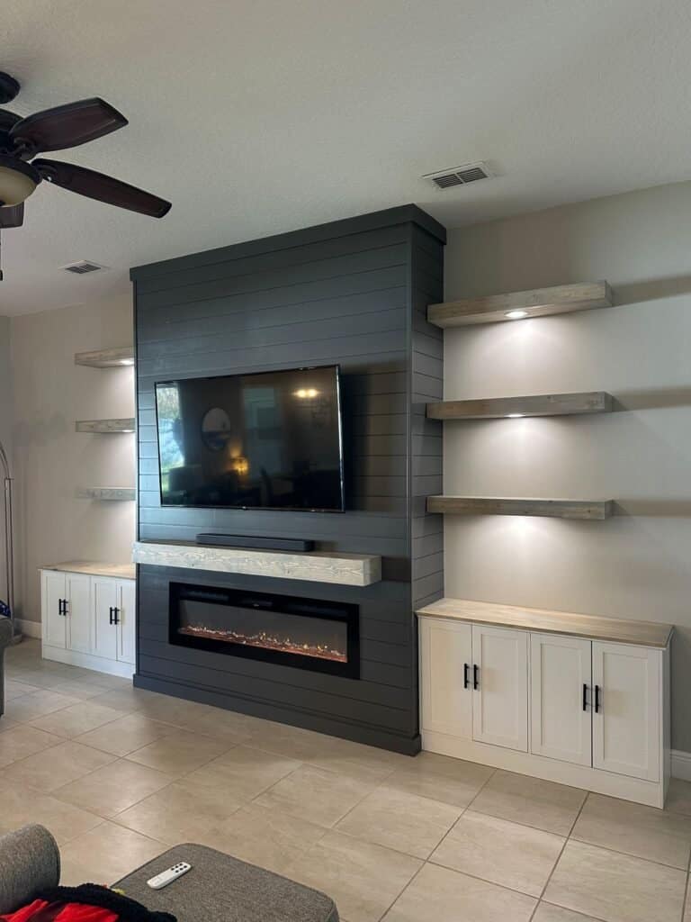 Black shiplap fireplace wall with floating shelves and electric fireplace in Florida