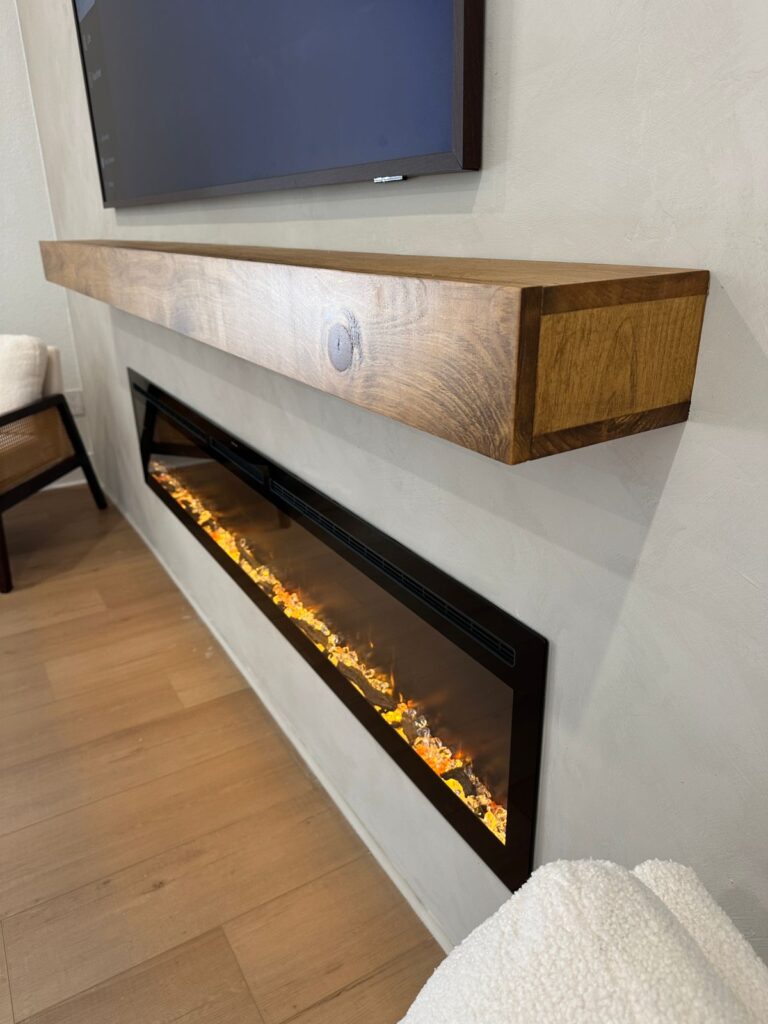 Classic fireplace wall with white painted brick, thick floating wood mantel, integrated electric fireplace, and traditional modern farmhouse styling.