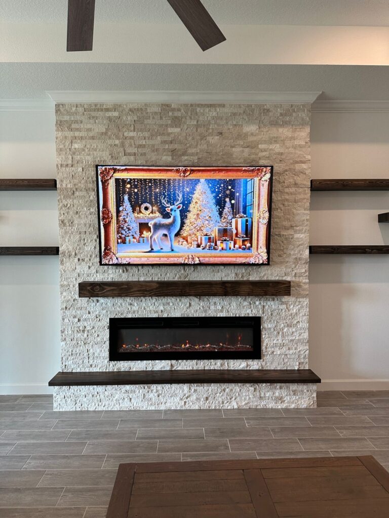 Custom linear fireplace wall with stone finish, floating wood mantel, recessed electric fireplace, and modern entertainment wall design in Florida.