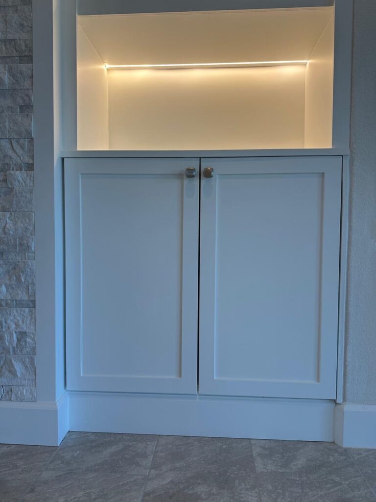 Built-in cabinet and LED shelf detail on custom stone fireplace TV wall