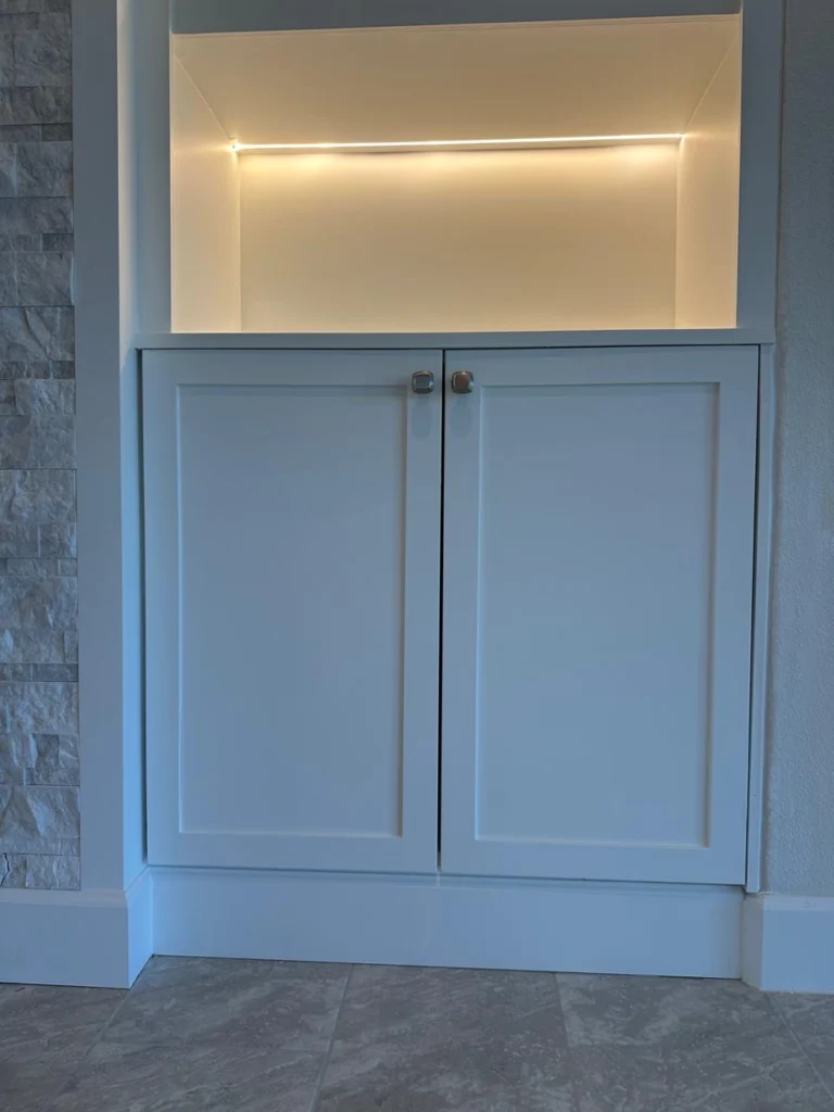 Built-in cabinet and LED shelf detail on custom stone fireplace TV wall
