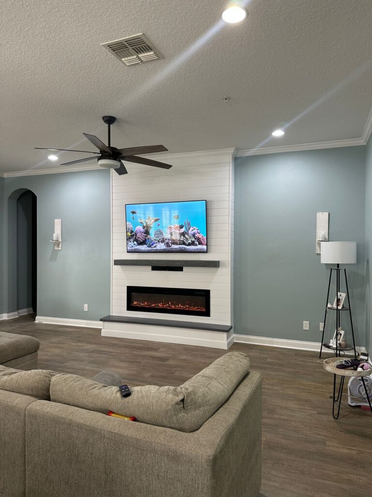 Minimal white shiplap fireplace wall with floating mantel, floating bench, TV mount, integrated soundbar, and linear electric fireplace