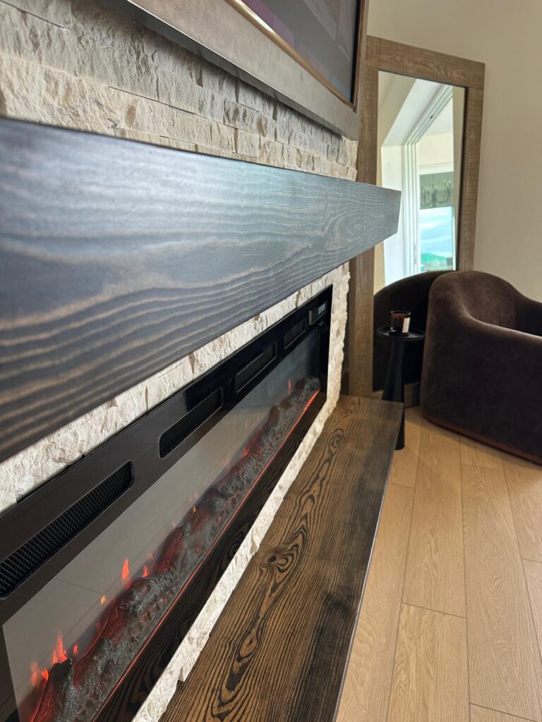 Stone fireplace media wall with linear electric fireplace, floating wood mantel, and matching bench detail
