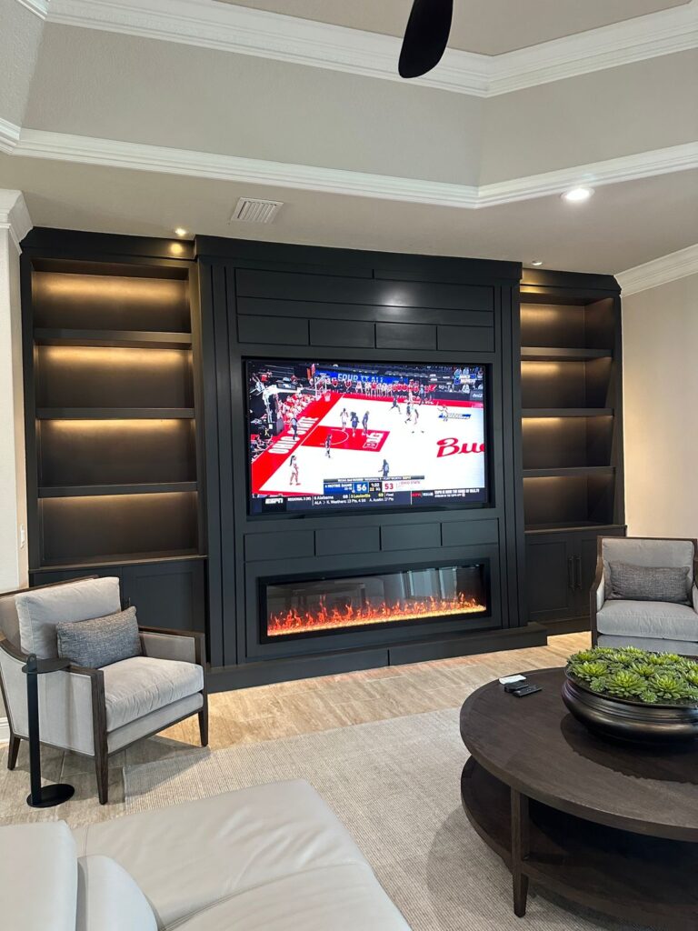 Luxury Dark Built-In Media Wall Dark built in media wall with recessed TV, LED shelves, lower cabinets, and linear electric fireplace