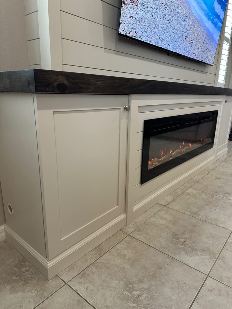 Built in base detail on white shiplap fireplace wall with dark countertop