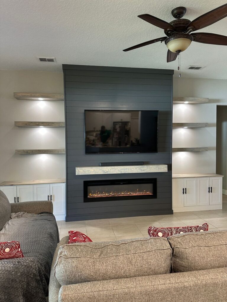 Fireplace TV wall with floating shelves, built-in cabinets, dark center wall, wood mantel, and linear electric fireplace