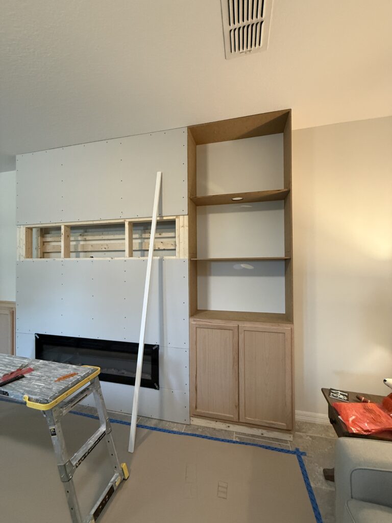 Classic stone fireplace wall construction with built-in cabinet section, fireplace opening, and wall framing