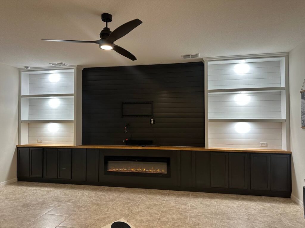 Fireplace TV wall with cabinets, LED shelving, black lower cabinets, shiplap finish, butcher block countertop, and linear fireplace