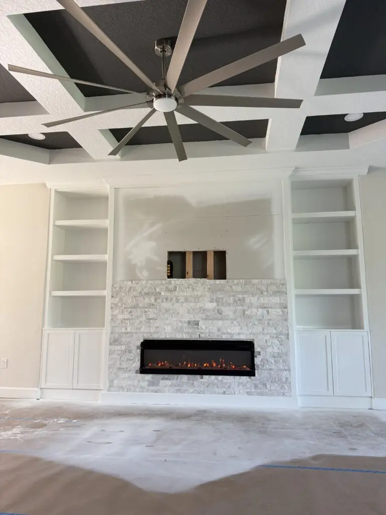 Custom stone fireplace TV wall before TV installation with LED shelving, built-in cabinets, and linear fireplace