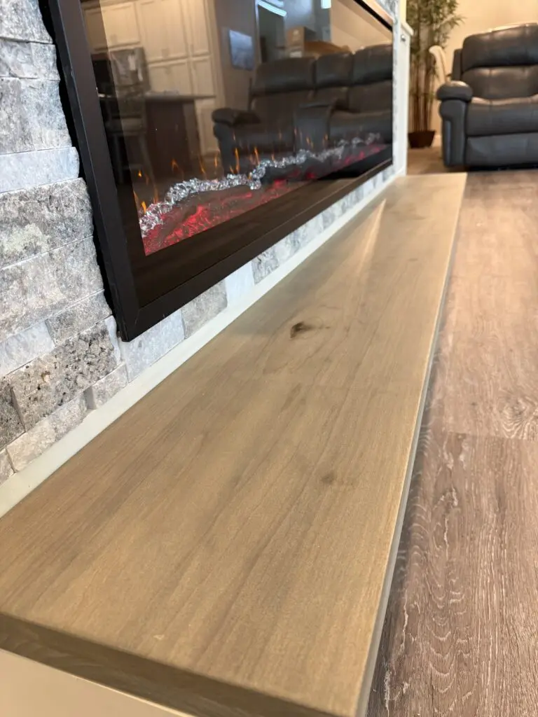 Linear electric fireplace with floating wood mantel on custom stone fireplace media wall