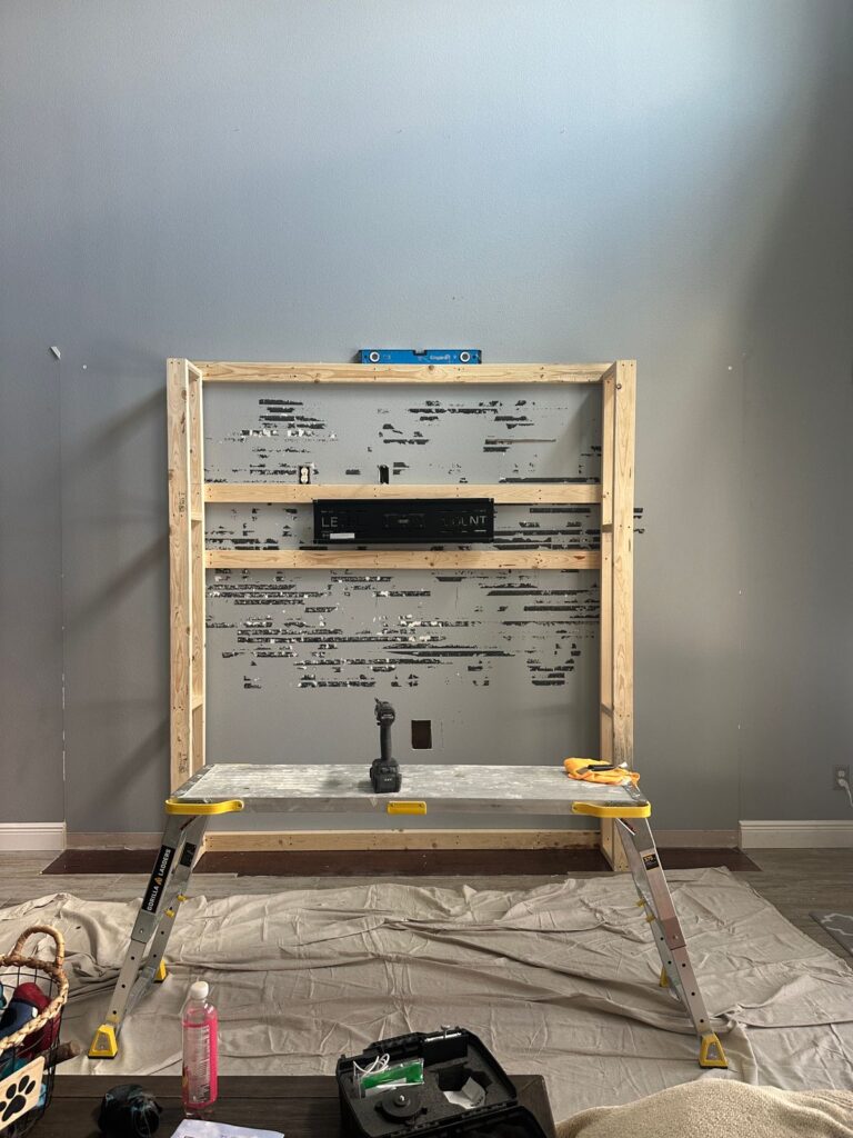 Framing stage for limestone fireplace entertainment wall with TV opening, electric fireplace area, and built-in cabinet layout