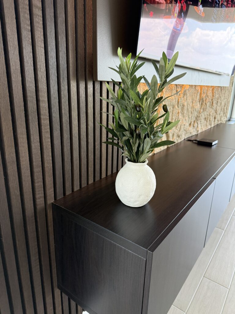 Floating cabinet detail on acoustic panel media wall with black wood slats and modern decor