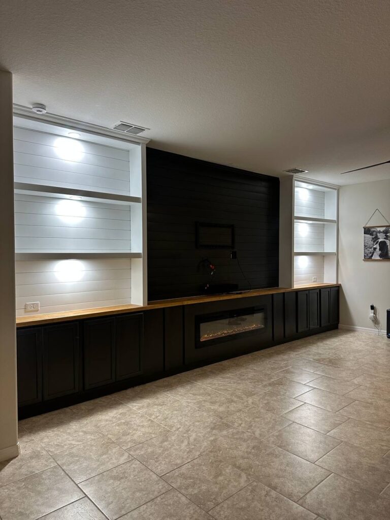 Finished fireplace TV wall with cabinets, LED shelves, black cabinetry, butcher block countertop, and electric fireplace