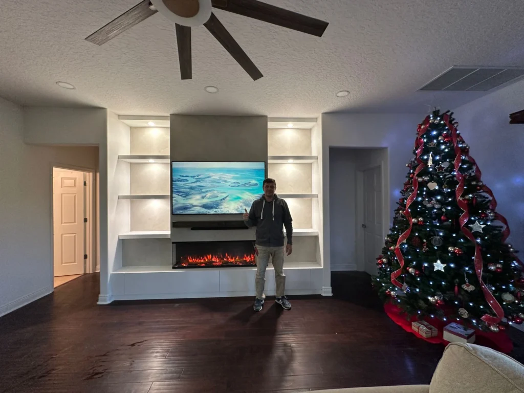 Modern living room with limewash fireplace TV wall, built in shelving, integrated lighting, and 3D fireplace
