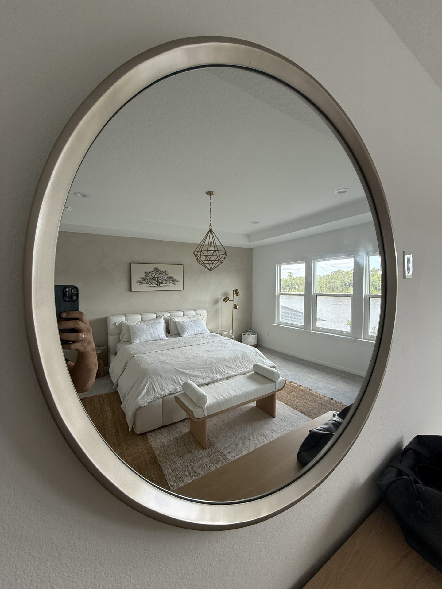 Minimal limewash accent wall reflected in round mirror in calm modern bedroom