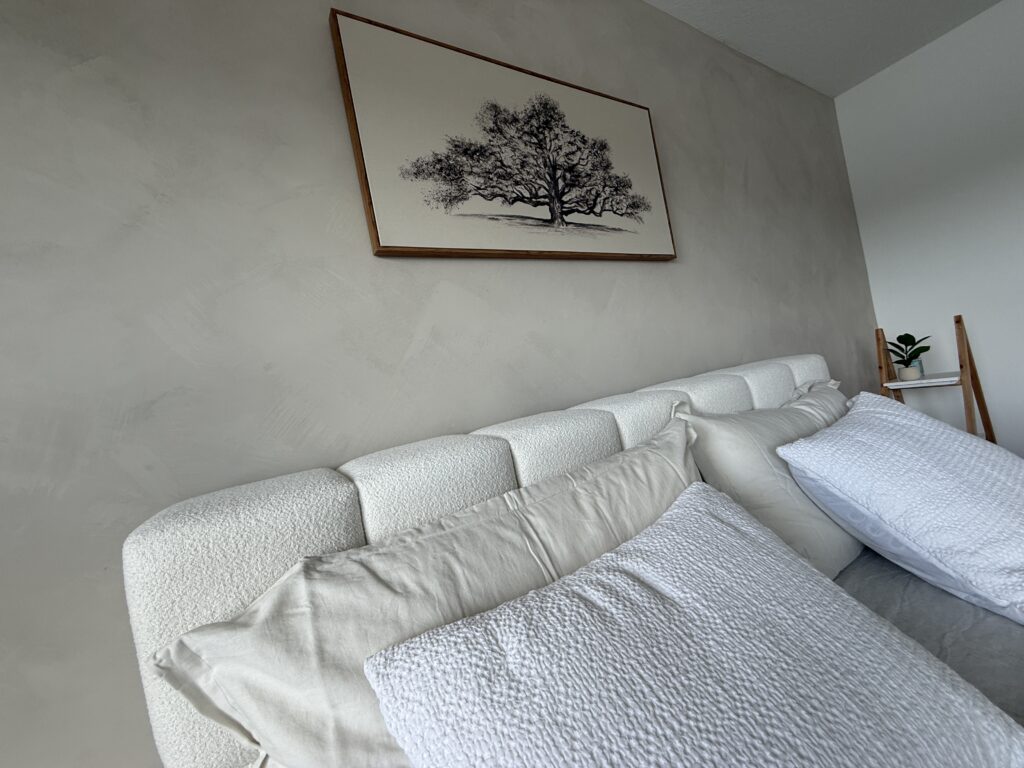 Minimal limewash accent wall with soft neutral texture behind bed in modern bedroom