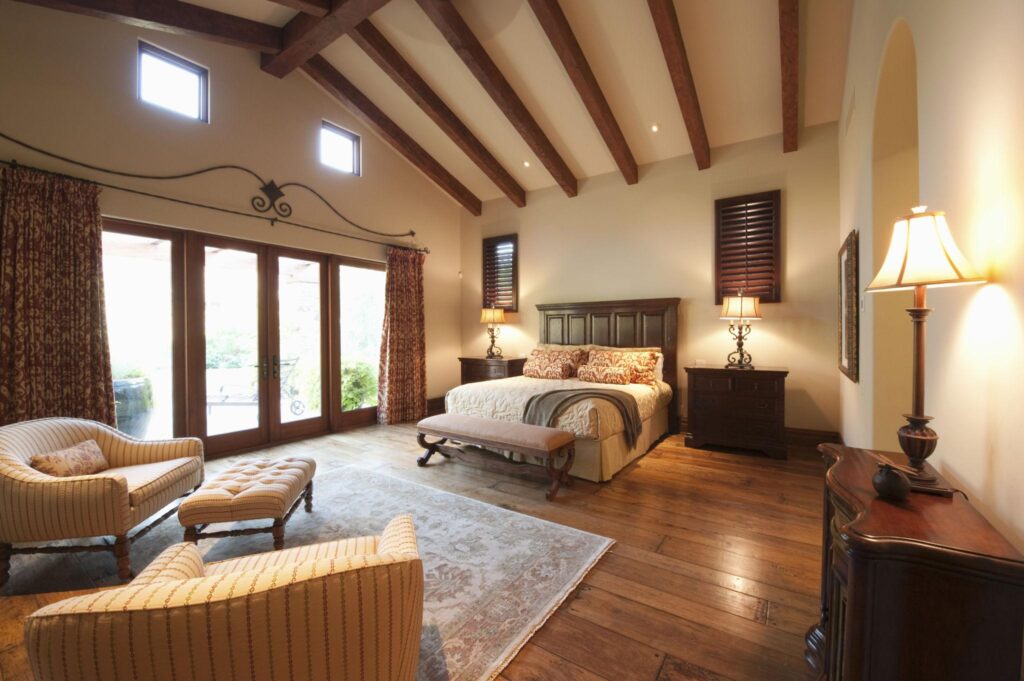 Rustic wood beam ceiling with exposed natural beams, warm bedroom styling, and large windows