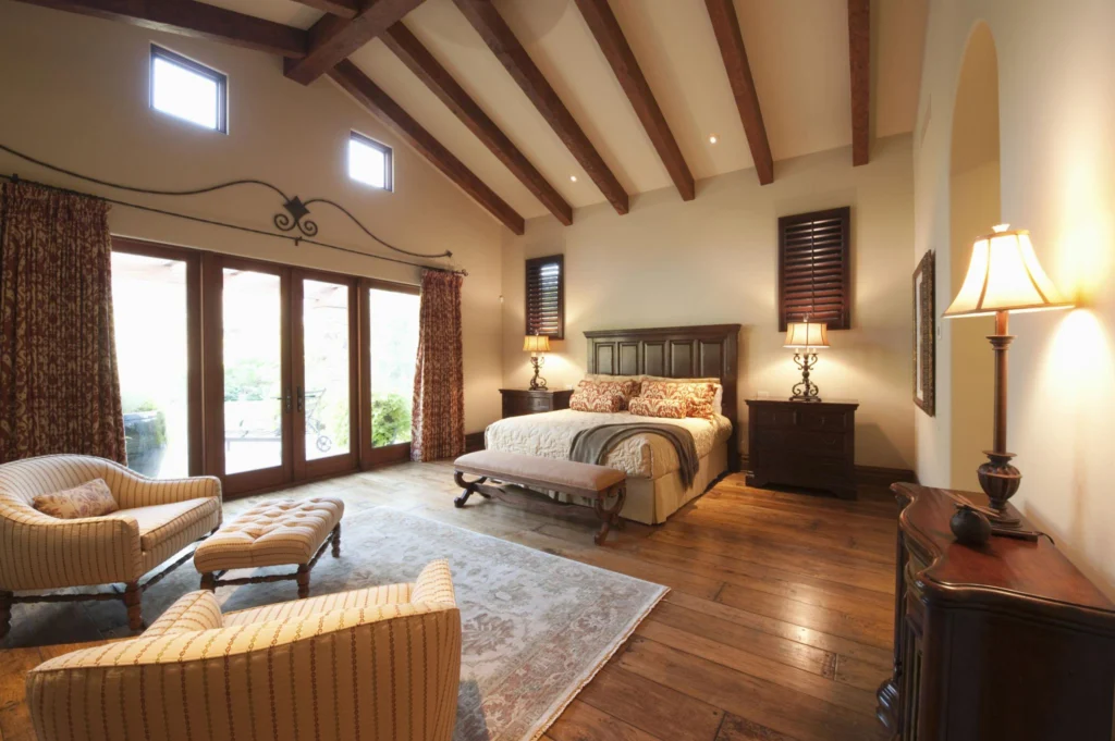 Rustic wood beam ceiling with exposed natural beams, warm bedroom styling, and large windows