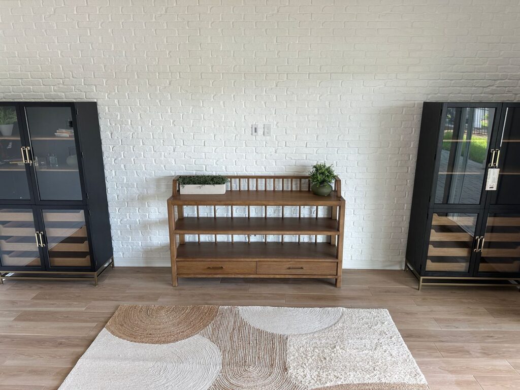 White brick accent wall with textured finish, wood console, black display cabinets, and modern dining room decor