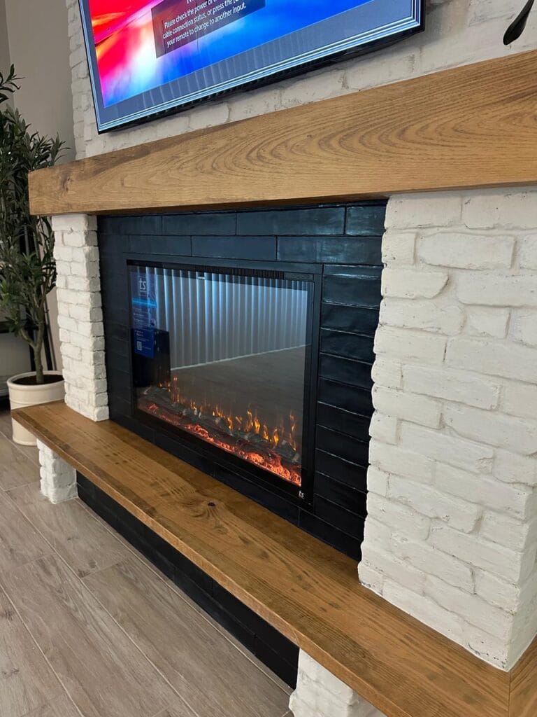 White brick fireplace wall with electric fireplace, black surround, custom wood mantel, and matching bench