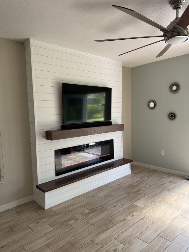 Angled view of the white shiplap media wall with TV and linear electric fireplace
