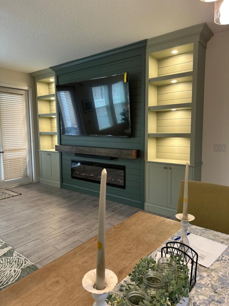 Windermere TV Media Wall with Built-Ins Near Orlando Custom TV media wall in Windermere near Orlando with built-in shelves, cabinets, wood mantel, and electric fireplace