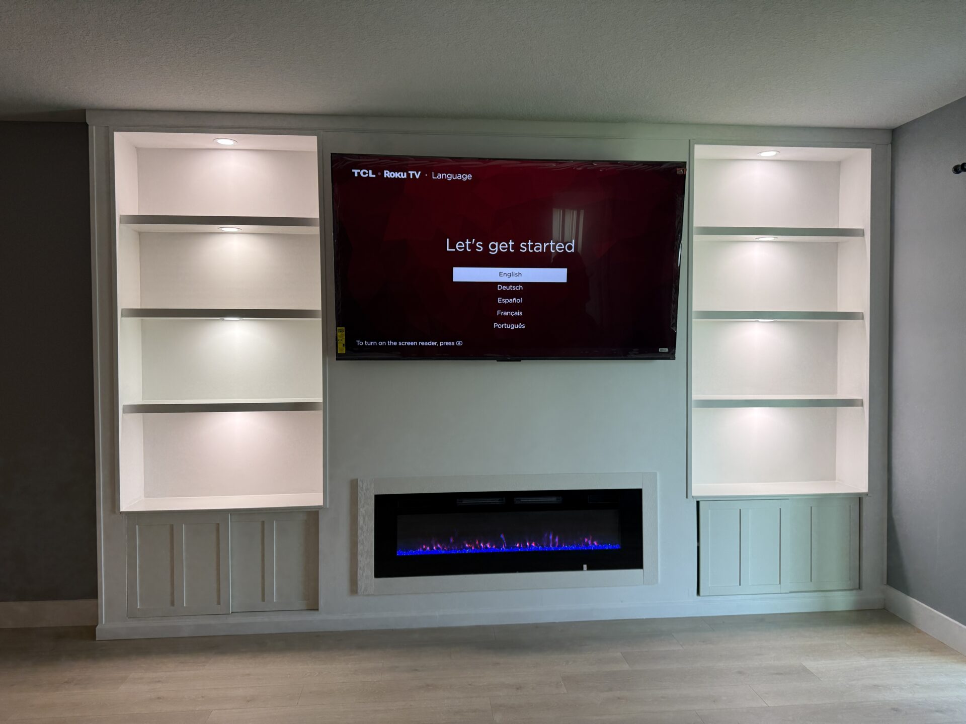 Front view of built-in cabinetry in Palm Bay with symmetrical lighted shelves, lower storage cabinets, and linear electric fireplace