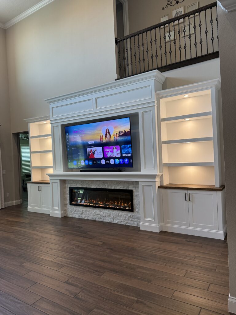 Luxury Custom Media Wall with Furniture-Grade Finish Luxury custom media wall with furniture-grade painted cabinets, wood countertops, stone fireplace surround, LED shelves, and TV layout