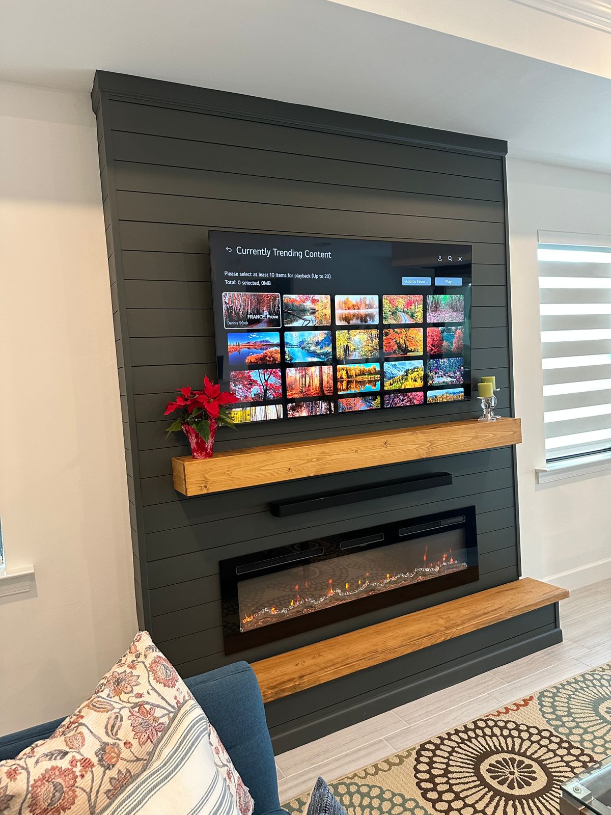 Dark Fireplace Media Wall in Tampa Fireplace media wall in Tampa with dark shiplap, wood mantel, linear electric fireplace, and mounted TV