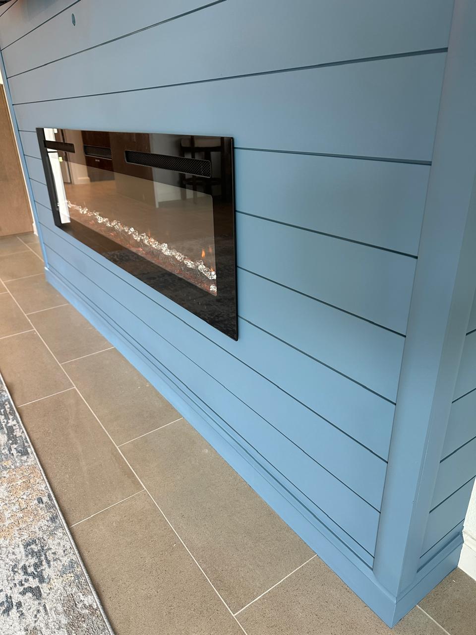 Close-up of linear electric fireplace installed in a blue shiplap fireplace wall in Tavares