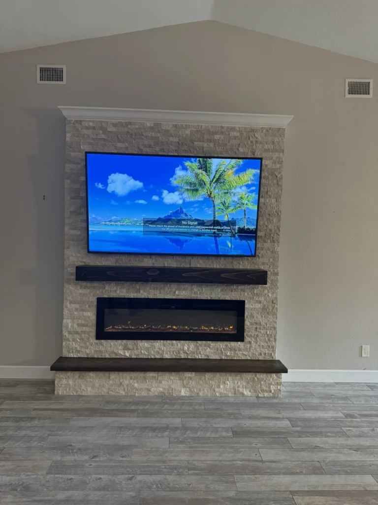 Completed ledger stone fireplace wall in Sanford with mounted TV, wood mantel, hearth bench, and crown molding