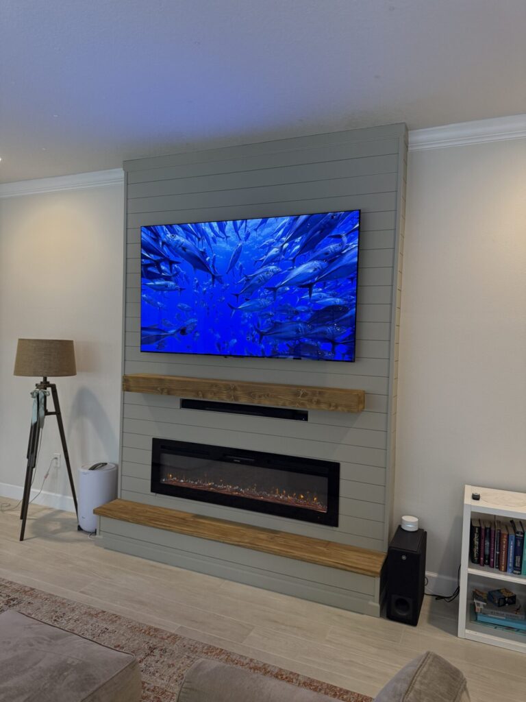 Completed sage shiplap fireplace wall with handcrafted wood mantel, bench and linear fireplace in Melbourne, Florida