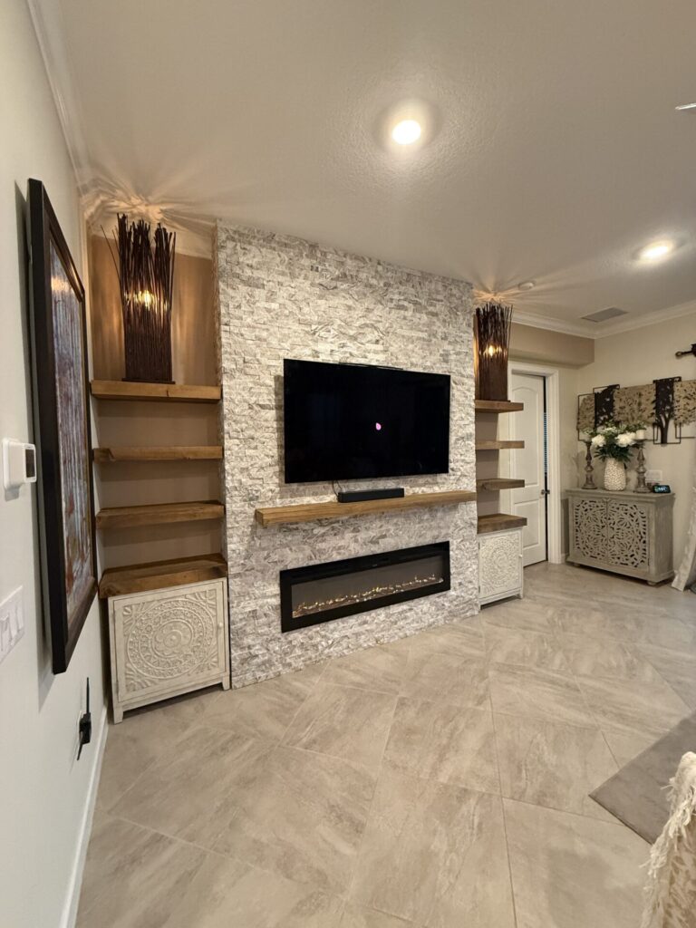 Side view of completed ledger stone fireplace wall with floating shelves and electric fireplace in Melbourne