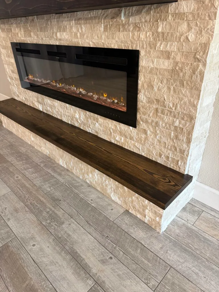 Linear electric fireplace with matching wood hearth bench on a ledger stone fireplace wall in Sanford