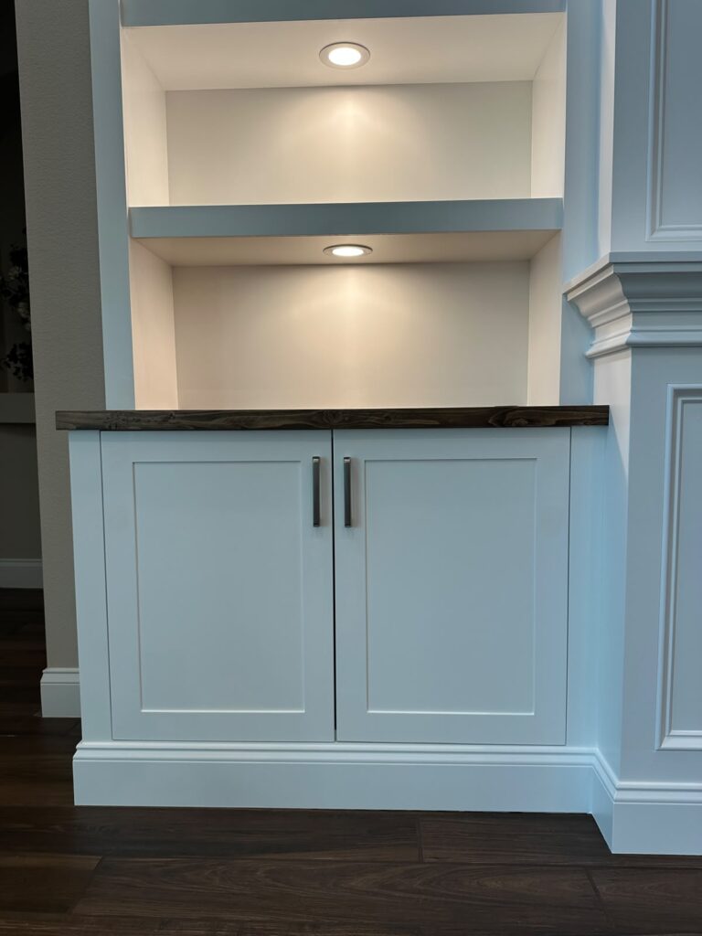 Custom Cabinetry with Illuminated Display Shelves Custom built-in cabinet with illuminated shelves and wood countertop