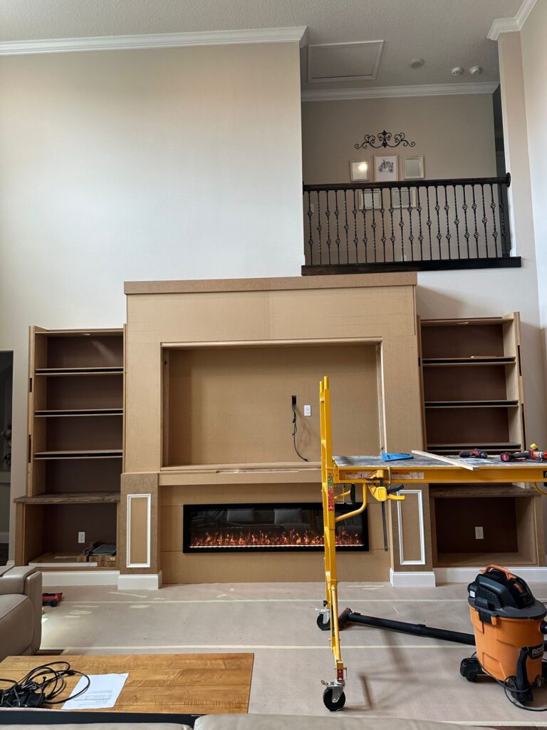 Luxury Built-In Media Wall Installation Process Luxury built-in media wall installation in progress with fireplace and shelving