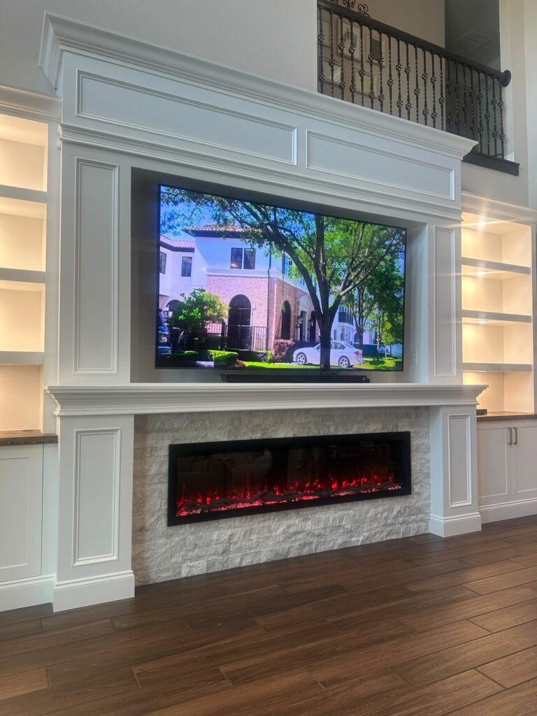 Completed Luxury Built-In Media Wall with Fireplace Luxury built-in media wall with fireplace, recessed TV, cabinets, and illuminated shelves