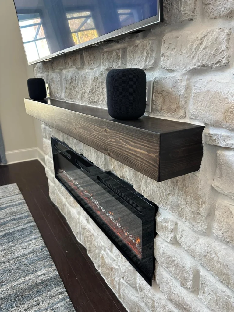 Custom Fireplace Wall Stone and Mantel Detail Orlando Custom fireplace wall in Orlando with stone finish, dark floating mantel, electric fireplace, and media wall detail