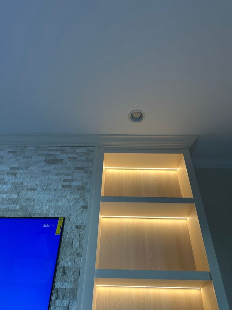 LED shelf lighting on a custom Orlando media wall with built-in shelving and stone fireplace detail