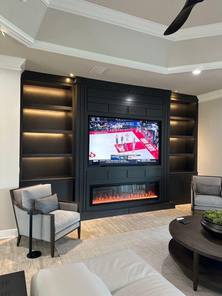 Black Custom Media Wall with Fireplace Modern black media wall with electric fireplace, custom shelving, and integrated LED lighting