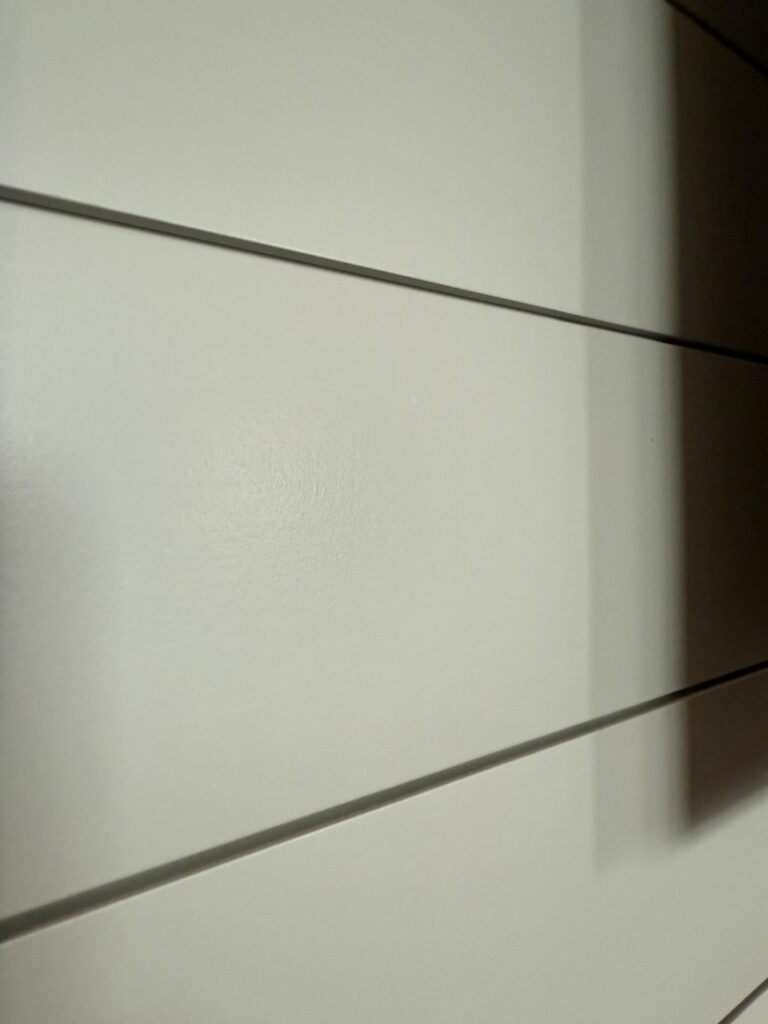 Close-up of the professional sage-gray paint finish on a custom shiplap fireplace wall