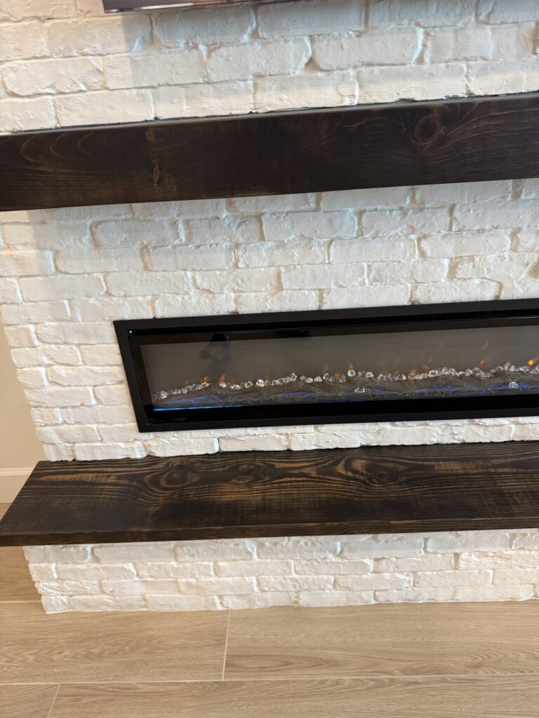 white-brick-fireplace-wall-in-orlando-linear-fireplace.jpg White Brick Fireplace Wall in Orlando featuring a large linear electric fireplace and handcrafted wood mantel
