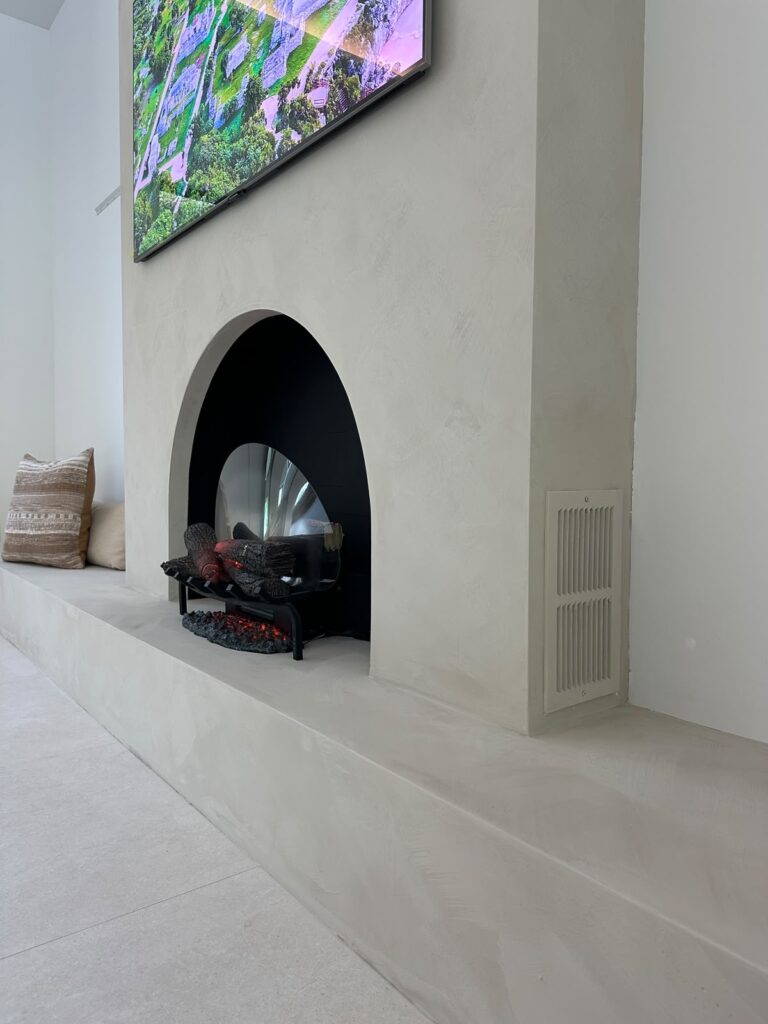Limewash fireplace wall Boca Raton with arched wood-burning firebox