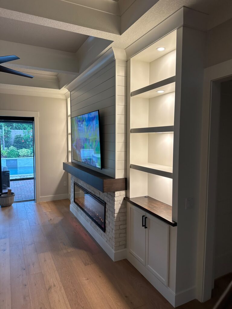 Completed brick and shiplap media wall with illuminated built-ins and custom cabinetry in Orlando