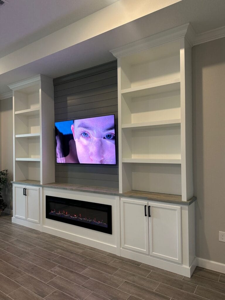 Completed Custom Media Wall — Palm Bay, Florida Completed media wall with a TV, linear fireplace, white built-in cabinets and open shelves in Palm Bay, Florida.