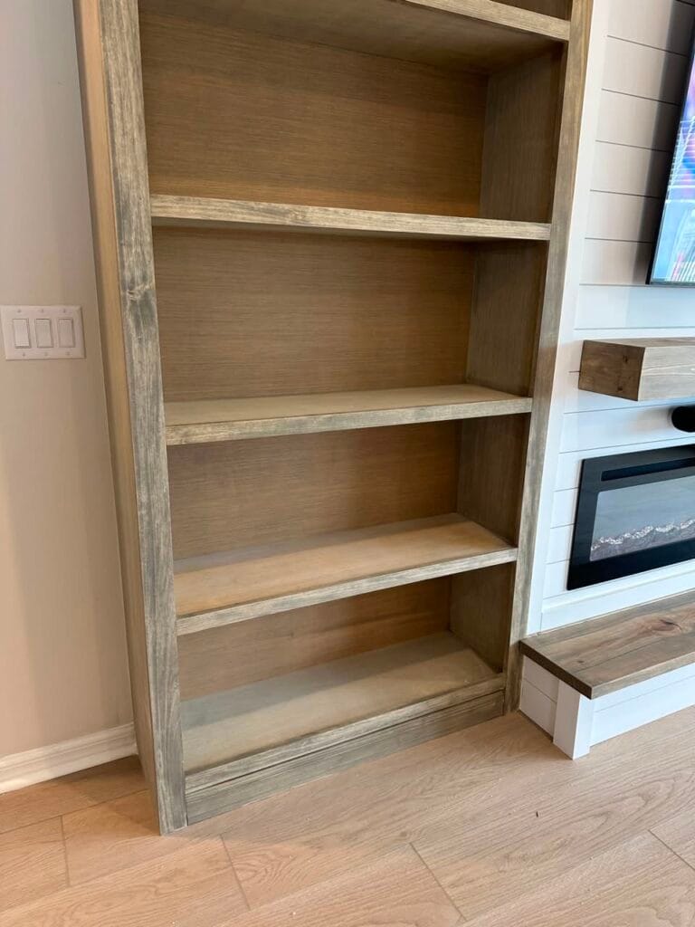 Stained and lacquered natural wood shelves beside the white shiplap fireplace wall
