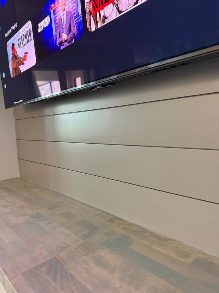 Gray Shiplap and Countertop Detail — Palm Bay Close-up of gray horizontal shiplap and a wood-toned countertop beneath the wall-mounted TV.