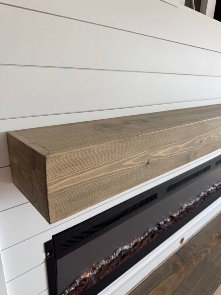 Handcrafted wood mantel detail on a white shiplap fireplace wall